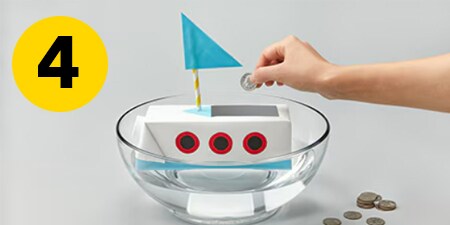 Step 4 - putting a coin into the crafted boat in a bowl of water to test buoyancy
